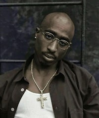 a black man wearing glasses and a cross necklace